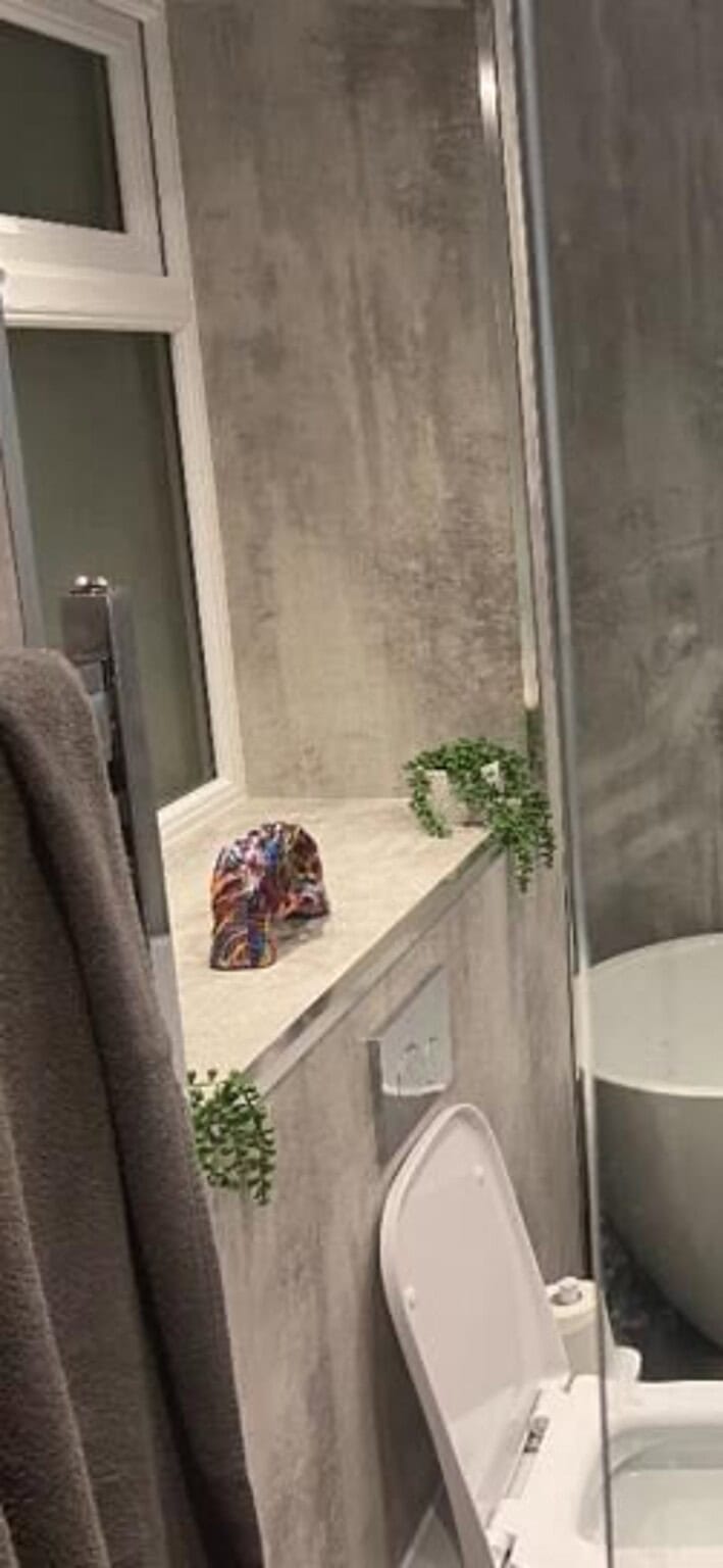 Modern bathroom with bathtub, toilet, and illuminated mirror in Exeter.